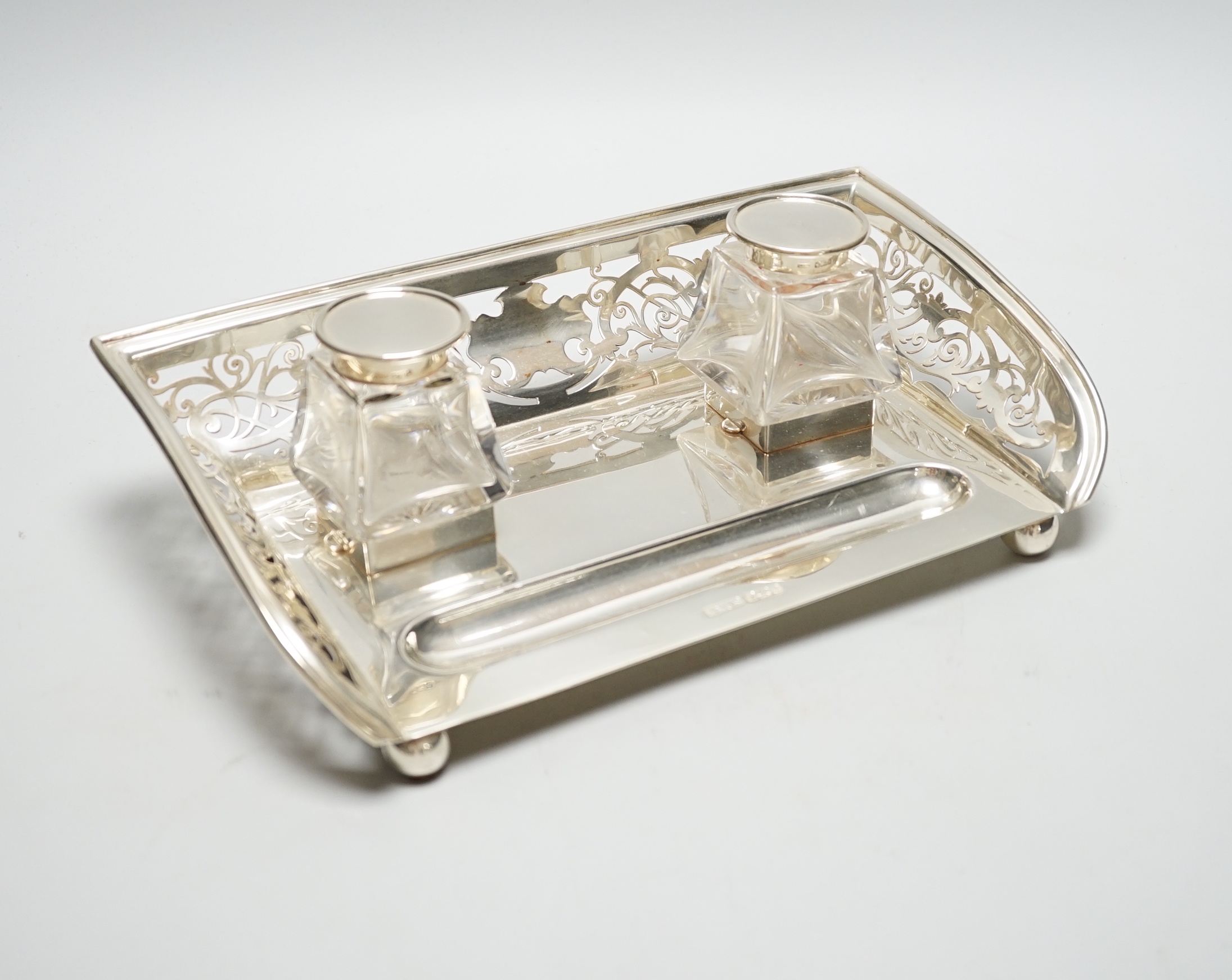 A George V pierced silver inkstand, with two mounted glass wells, Mark Willis & Son, Sheffield, 1912, length 29cm, base 21.7oz.